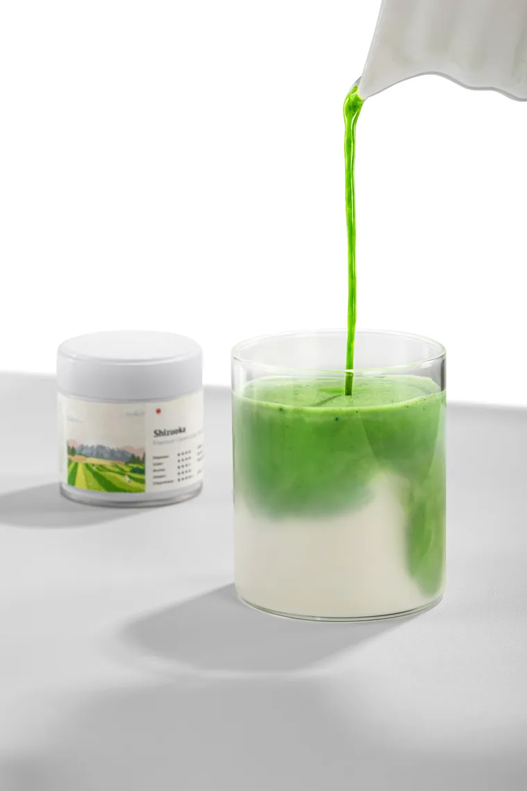 A stream of matcha poured into a glass of milk