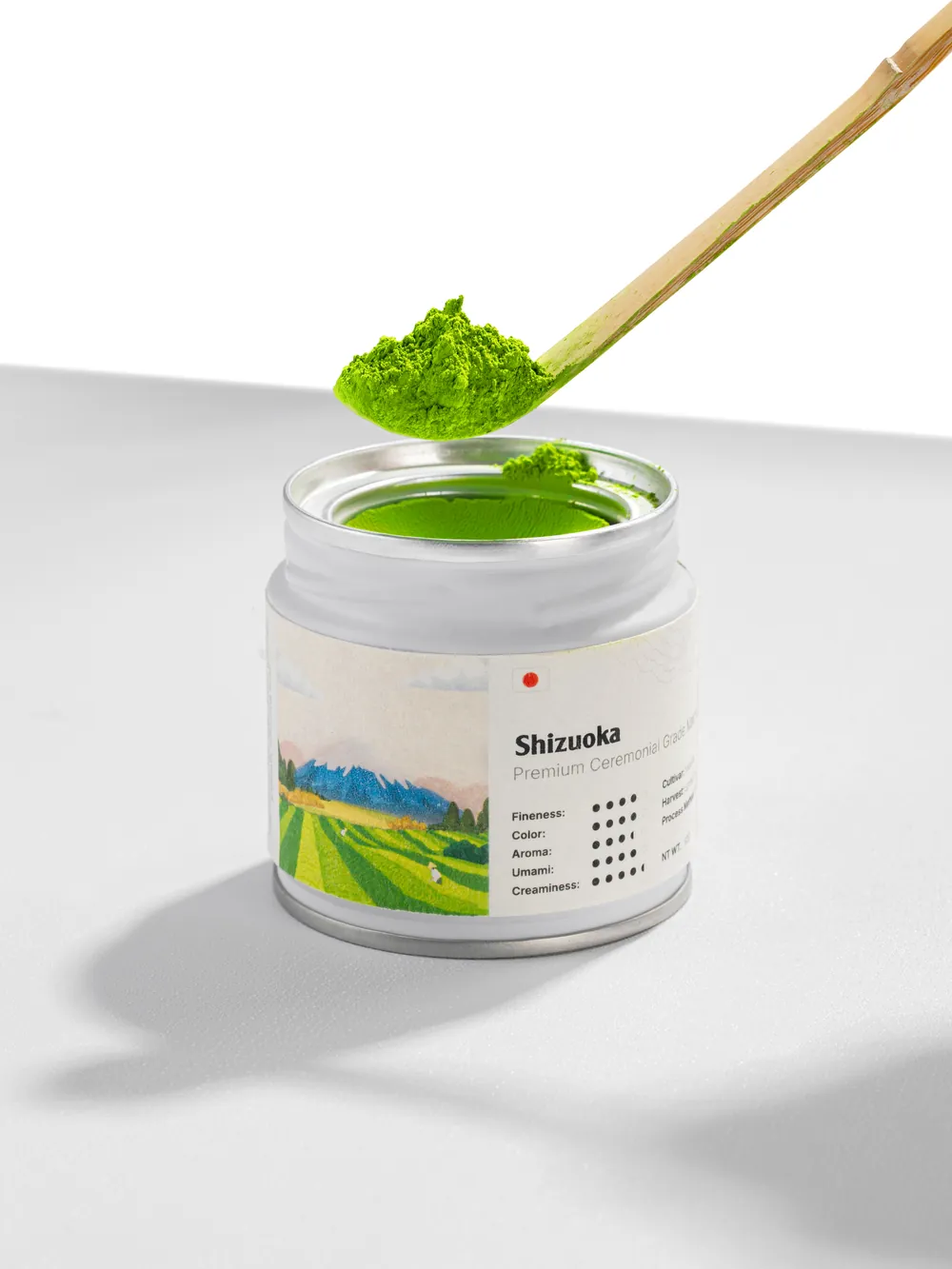 A bamboo scoop of matcha held over an open M'atelier tin